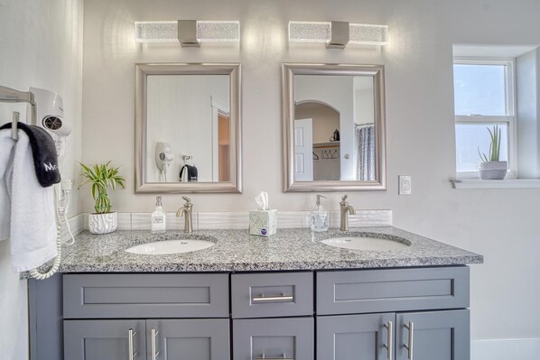 A bathroom with two sinks, a mirror, and a towel rack.