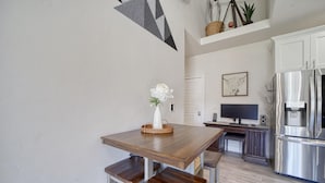 A modern kitchen with a wooden table, bench seating, a large refrigerator, and a television. - The Jolly Rancher, Luxury Amenities, Corporate and Vaca (Twin Falls)