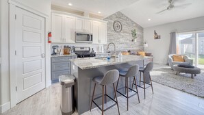 A modern kitchen with white cabinets, a granite island with bar stools, a microwave, and a sink. - The Jolly Rancher, Luxury Amenities, Corporate and Vaca (Twin Falls)