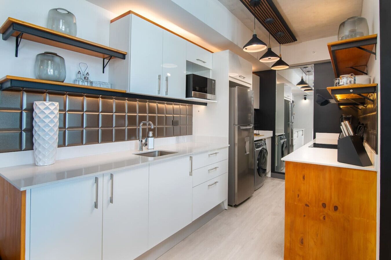 A modern kitchen with white cabinets, a stainless steel refrigerator, and wooden accents.