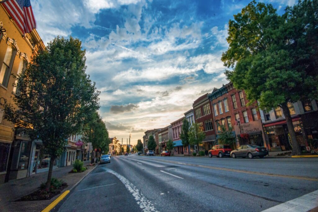 A street lined with historic buildings, a clear sky, and a few cars parked along the road.