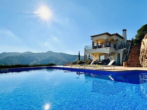 Una casa de dos pisos con piscina, balcón y vistas a las montañas.