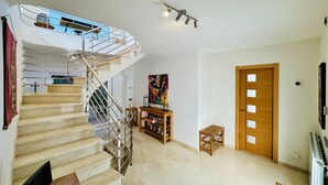 Een ruime woonkamer met een spiltrap, een houten deur en een radiator.