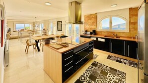Een moderne keuken met een centraal eiland, zwarte kasten en een groot raam.
