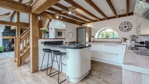 Een moderne keuken met een centraal eiland, houten balken en een groot raam.