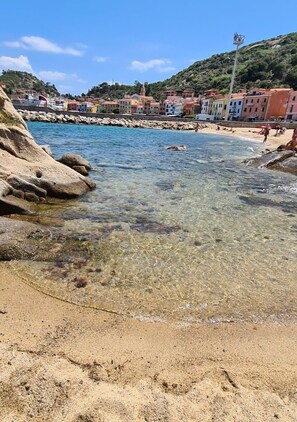 A coastal town with clear waters, rocky shoreline, and colorful buildings.