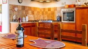 Una cocina con armarios de madera, una estufa y una botella de vino sobre la mesa.