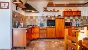 Una cocina con gabinetes de madera, estufa, horno y comedor con mesa y sillas.