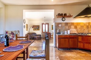 Un coin repas avec une table et des chaises en bois, une cuisine avec des meubles en bois et une cuisinière, et un salon avec un canapé et une table basse.