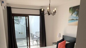 Ein Schlafzimmer mit Bett, Nachttisch, Lampe und Blick auf den Balkon.