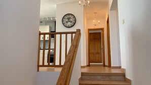 Eine Treppe mit Holzgeländern führt zu einem Raum mit einer Holztür und einer Wanduhr.