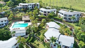 Un resort con diversi edifici, una piscina e vegetazione lussureggiante.