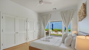 Un dormitorio con cama, ventilador de techo, vistas al exterior y ventana con cortinas.