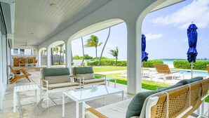 Un espacio al aire libre cubierto con piscina, sillones de descanso y vista al océano.