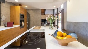Une cuisine moderne dotée d’un îlot central, d’un four encastré et donnant sur l’espace de vie.