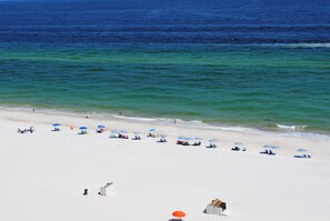 A beach with white sand and clear blue water. There are several umbrellas and people relaxing on the beach. - Summer House 1203B | Gulf-Front 3BR | Sleeps 10 (Orange Beach)