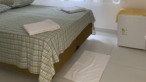 Et soveværelse med seng, puder, et sengebord, et vindue med gardiner og en radiator.