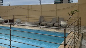En swimmingpool med gelænder i metal, omgivet af stentilefliser og plantekasser.
