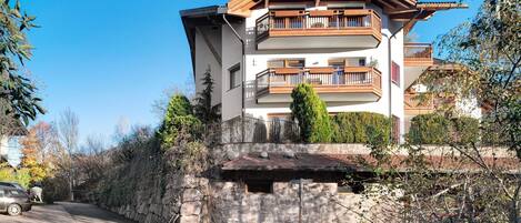 A multi-story building with balconies, a stone facade, and a clear sky.