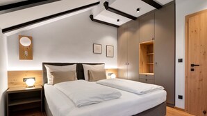 A bedroom with a bed, nightstands, a wooden door, and a built-in wardrobe.