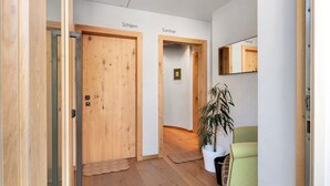 A hallway with wooden doors labeled 'Schlern' and 'Santner,' a potted plant, and a green chair.