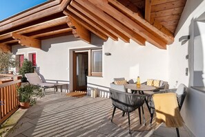 Eine Terrasse mit Holzboden, Sitzgelegenheiten im Freien und einer Tür zum Innenbereich.