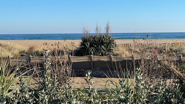 A beach with a sandy foreground, a wooden structure, and the ocean in the background.