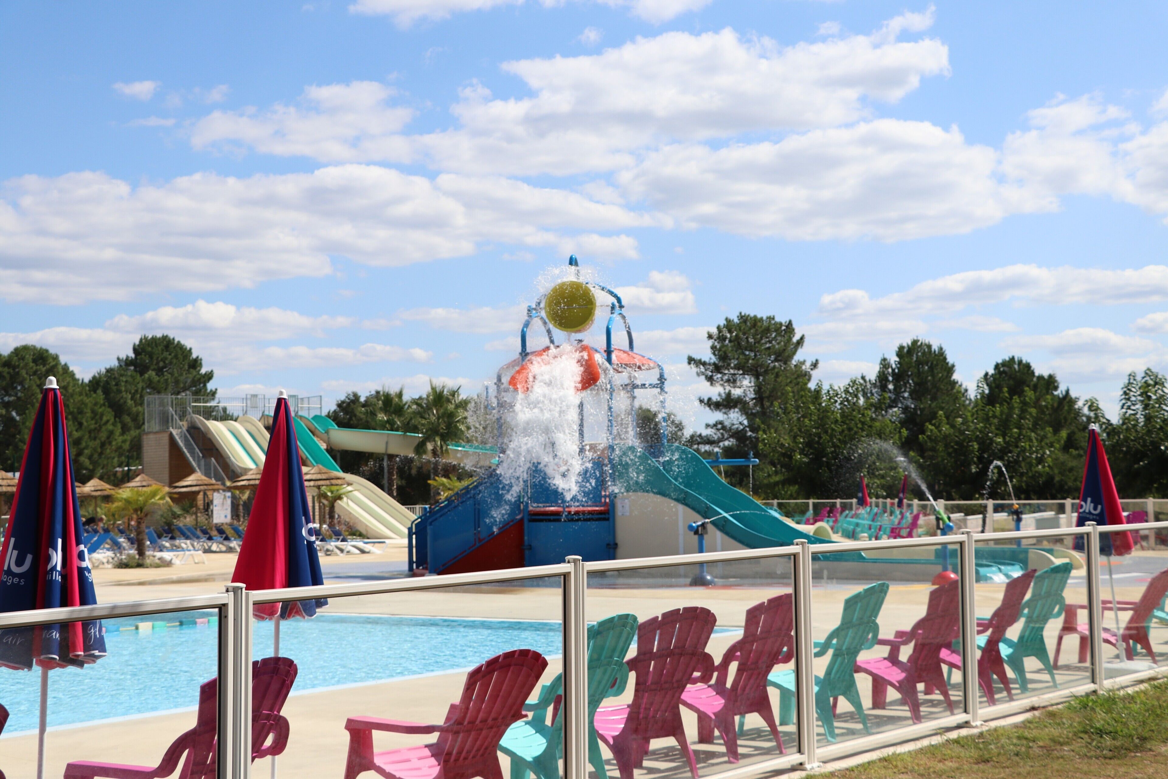 En swimmingpool med vattenrutschkanor, solstolar och parasoller.
