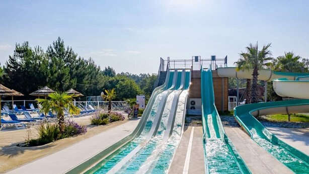 Un parc aquatique doté de nombreux toboggans, d’une zone de piscine et de chaises longues.