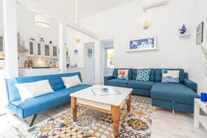 Una sala de estar moderna con un sofá azul, una mesa de centro blanca y un tapete estampado.