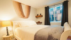 A neatly arranged bedroom with a bed, bedside lamp, and a window with curtains. - Windsor Retreat Private Basement Suite (Denver)