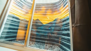 A window with a view of a mountain range and a sunset. - Windsor Retreat Private Basement Suite (Denver)