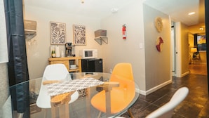 A modern kitchen with a glass table, white and orange chairs, a microwave, and a coffee maker. - Windsor Retreat Private Basement Suite (Denver)