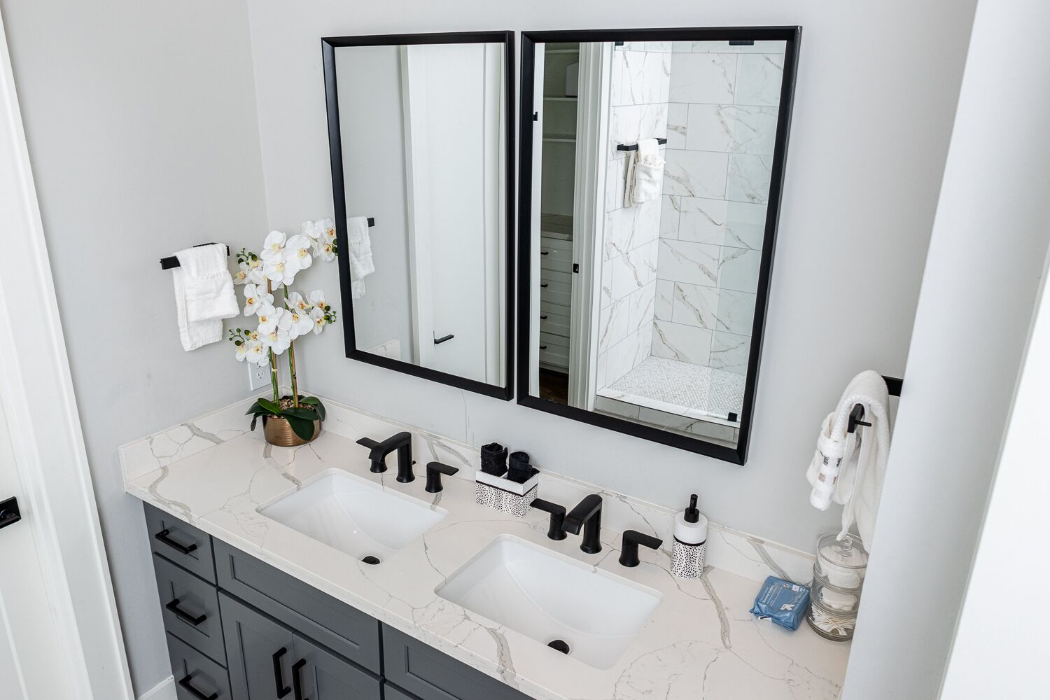 Une salle de bain avec deux lavabos, un grand miroir et une douche.