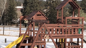 Una estructura de juegos de madera con un tobogán y elementos para escalar, rodeada de nieve.