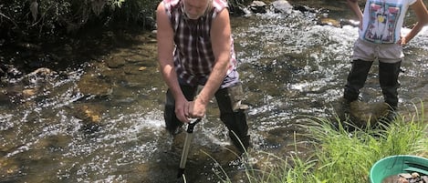 Two people by a stream with green buckets.