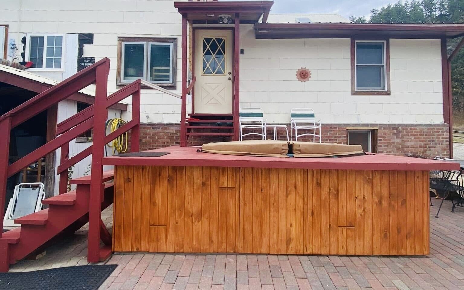 A wooden outdoor bar with a red roof, a staircase, and a white building in the background.