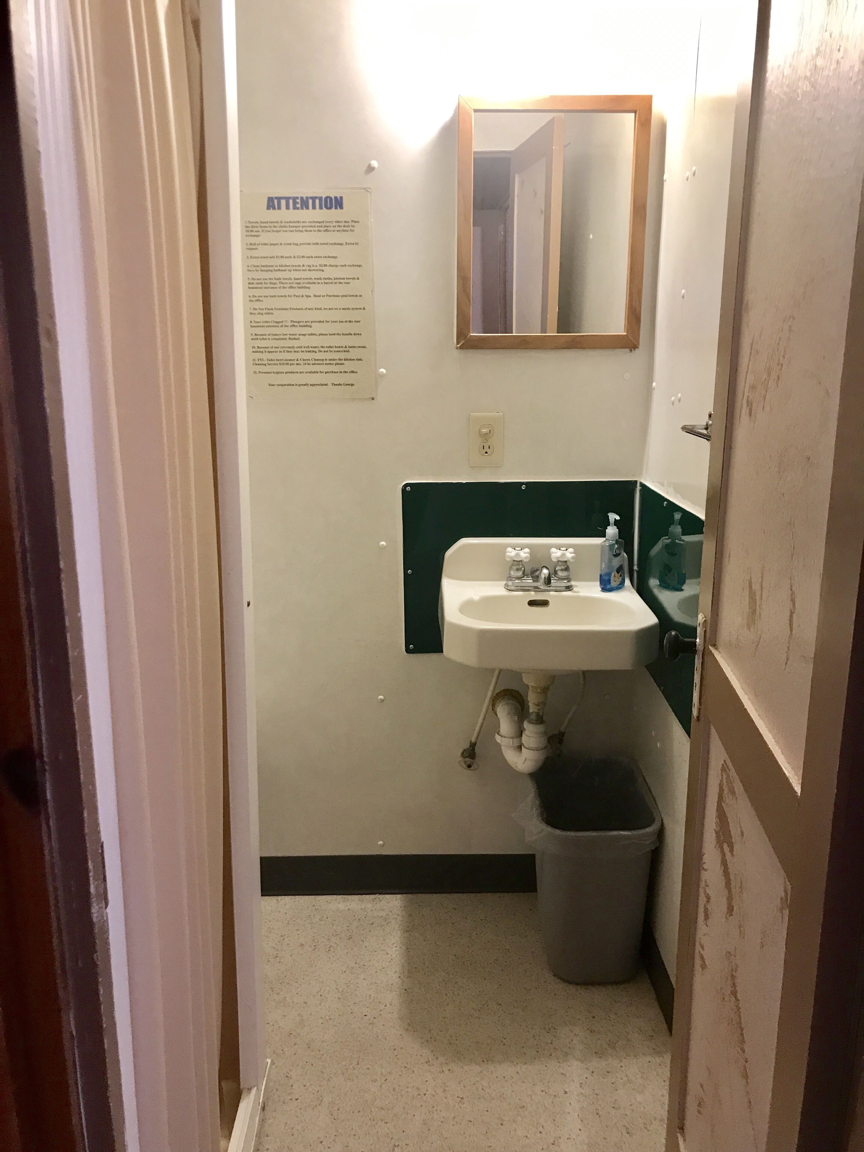 Ein kleines Badezimmer mit Waschbecken, Spiegel und Mülleimer.
