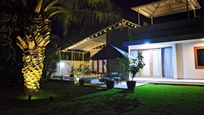 A modern house with a swimming pool, outdoor seating, and a covered patio area.