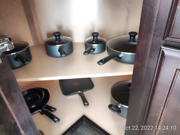 A kitchen with various pots and pans on shelves.