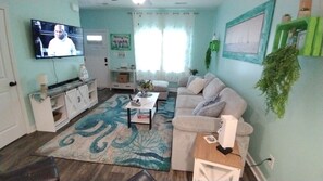 A living room with a television, sofa, coffee table, and a patterned rug.