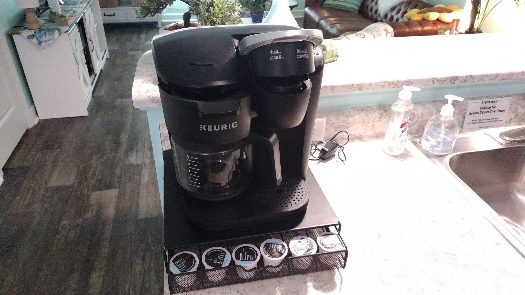 Eine Keurig-Kaffeemaschine mit Tropfschale und Kaffeekapseln auf einer Küchenarbeitsplatte.