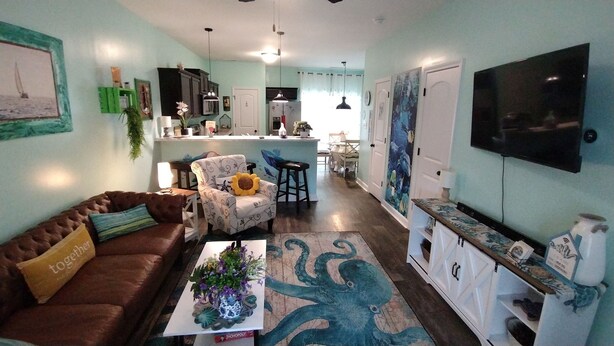 A living room with a brown sofa, a coffee table with a plant, and a patterned rug. - Beachy style and cosy. Book your own little hotel.No pet FEE, 4 Guests. (Sneads Ferry)