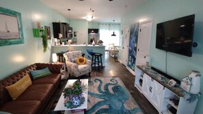 A living room with a brown sofa, a coffee table with a plant, and a patterned rug.