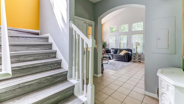 A staircase with white railings leading to a living area with a sofa and a coffee table. - Unit 27 | 4BR Home | 2 Mi to Disney | Pet Friendly | Gated Resort (Kissimmee)