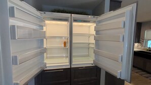 A modern kitchen with a built-in refrigerator, a countertop, and a staircase leading to an upper level.