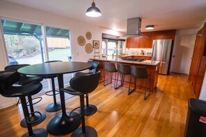 A modern kitchen with a central island, bar stools, and a dining table. - 6BR-Spacious-Bright-Modern (Eugene)