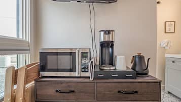 A kitchenette with a microwave, coffee maker, kettle, and a small cabinet with drawers.