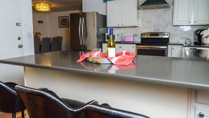 Eine moderne Küche mit weißen Schränken, einem Edelstahlkühlschrank, einer Weinflasche und einem rosa Toaster.