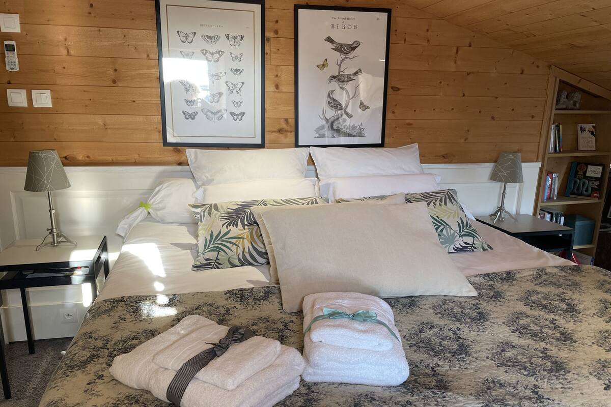 Een net opgemaakt bed met beddengoed met bloemenprint, twee kussens en twee opgevouwen handdoeken.
